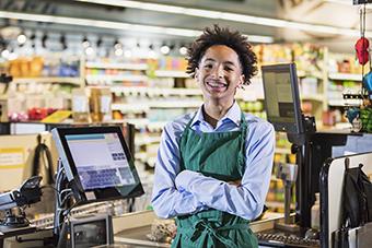 Teen boy smiling at cash register in grocery store