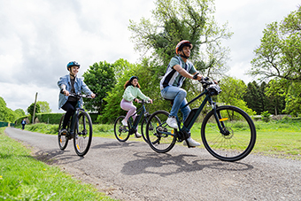 Three teenagers riding e-bikes at the park, wearing helmets