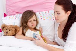 Sick child and mom looking at a bottle of cough syrup