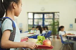 Girl looks for a seat in a school cafeteria