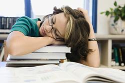 Teen girl sleeping on her textbooks
