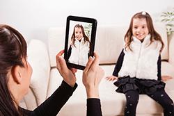 Mom taking photo of daughter with tablet