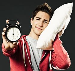 Teen with pillow and alarm clock