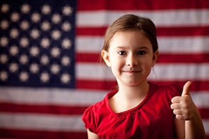 Girl giving thumbs up in front of an American flag