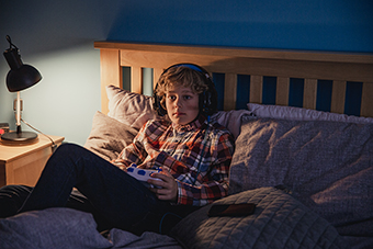 Boy playing video games in bed