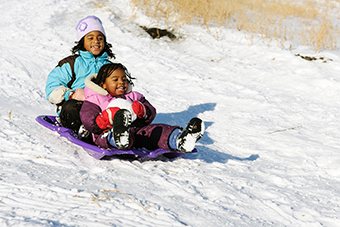 Two young girls sledding