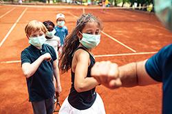 kids playing tennis in masks